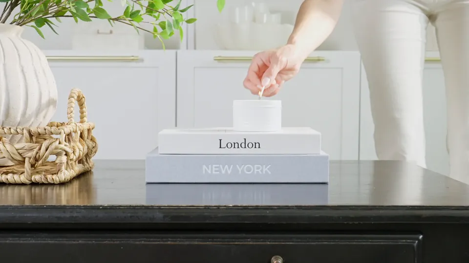 Hand lifting the lid of a linen book box on a styled console