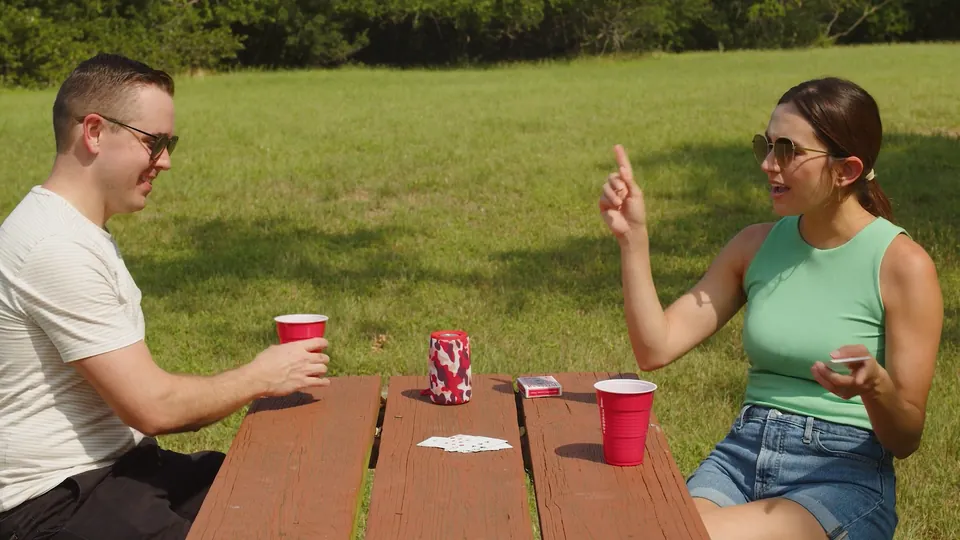 Friends playing cards at a picnic table with a portable speaker