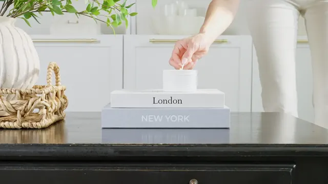 Hand lifting the lid of a linen book box on a styled console table