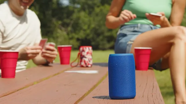 Portable Bluetooth speaker on a picnic table during a card game